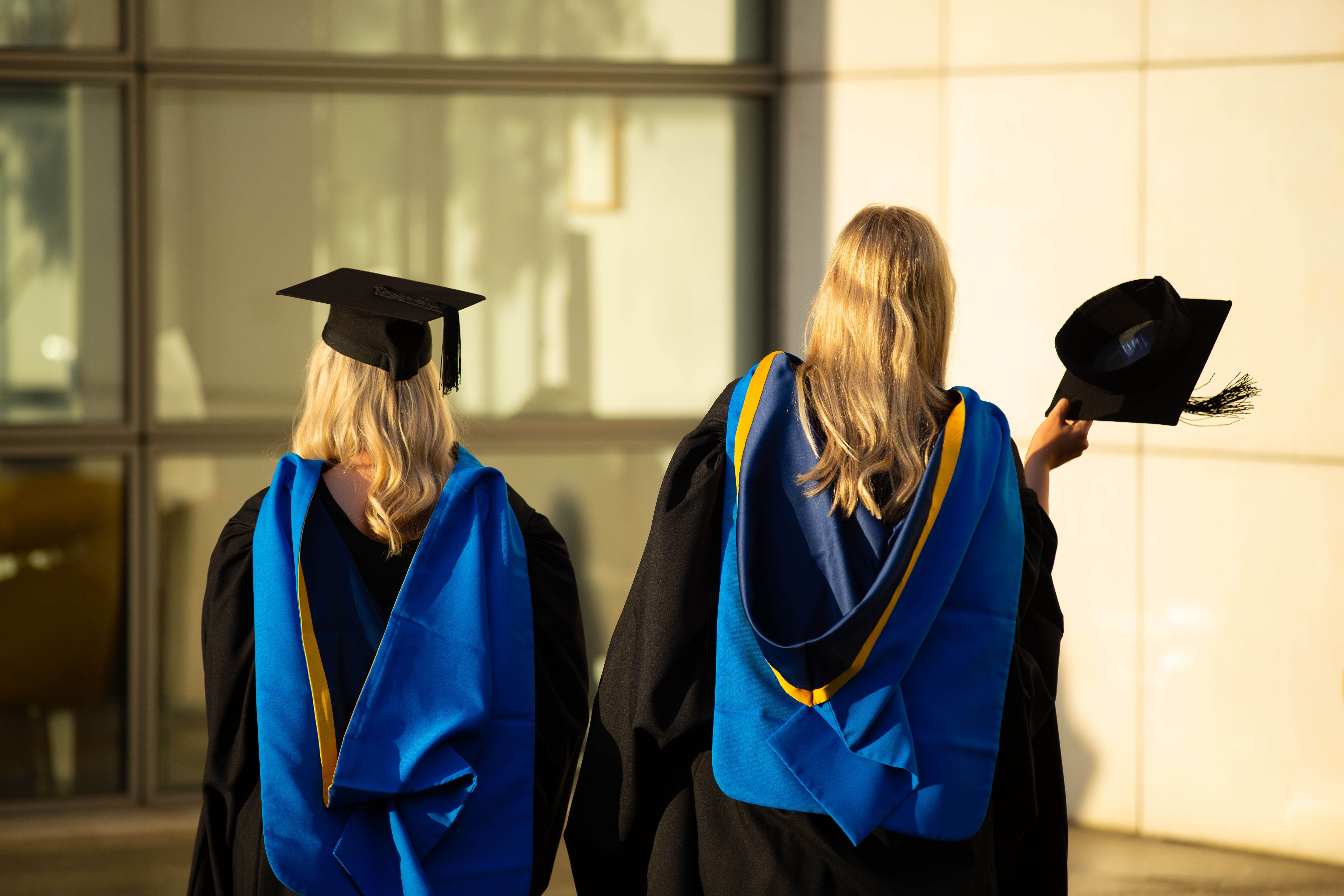 Two blonde graduates photographed from the back wearing UCD graduation robes